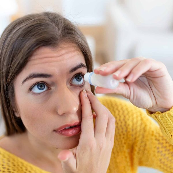Woman using eye drop after visiting our dry eye clinic and getting her unique treatment